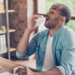 Man sneezing at a desk