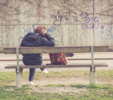 Back view of  a woman sitting alone on a park bench